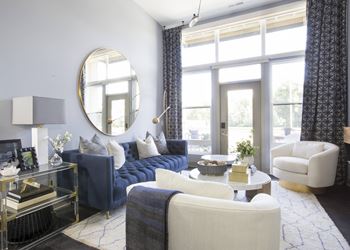 a living room with blue and white furniture and a round mirror on the wall  at Avant & Avant II, Carmel, 46032